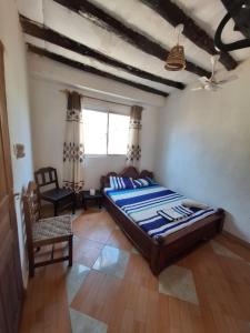 a bedroom with a bed and a chair and a window at Masai 2 in Diani Beach