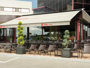 a restaurant with chairs and tables and a building at Ibis Schiphol Amsterdam Airport in Badhoevedorp