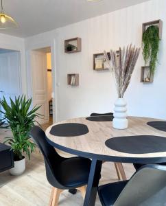 a dining room table with black chairs and a vase with plants at Appart' Porte Saint-Pierre in Pontarlier +7 photos