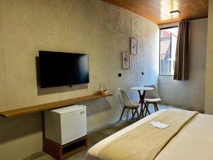 a hotel room with a bed and a flat screen tv at Villa Aracê in São Miguel dos Milagres