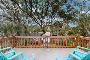 two blue chairs sitting on a deck with a tree at The Treehouse at 10th in Folly Beach