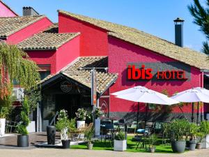 een rood gebouw met parasols voor een restaurant bij ibis Macon Sud Crêches in Crêches-sur-Saône