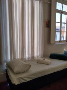 a bed with two towels on it in a room with a window at Pousada Divino Espírito Santo in Paraisópolis