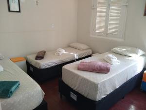 a room with three beds with towels on them at Pousada Divino Espírito Santo in Paraisópolis