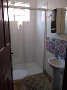 a bathroom with a shower and a toilet and a sink at Pousada Divino Espírito Santo in Paraisópolis