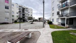 a bench in the middle of a courtyard with buildings at Acogedor departamento en La Serena in La Serena