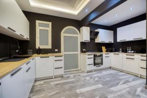 a large kitchen with white cabinets and a tile floor at Host Prime Villas in Cairo