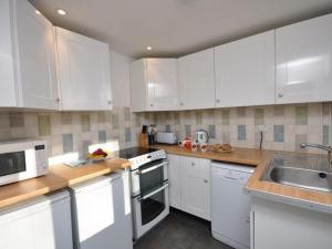una cocina con armarios blancos y electrodomésticos blancos en 2 Bed in Bigbury-on-Sea KEMTH, en Ugborough