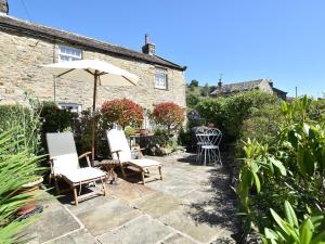 a patio with chairs and an umbrella in front of a house at 1 Bed in Richmond 36769 in Reeth