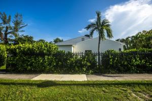 a white house with a palm tree behind a fence at The Side Villa in Miami