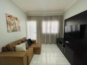 a living room with a couch and a flat screen tv at Flat Centro 301 in Tangara da Serra