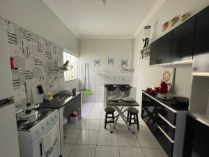 a small kitchen with a stove and a counter with stools at Flat Centro 301 in Tangara da Serra