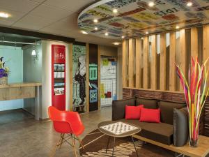 un hall d'entrée avec un canapé et une chaise rouge dans l'établissement ibis Saint Rambert d'Albon, à Saint-Rambert-dʼAlbon
