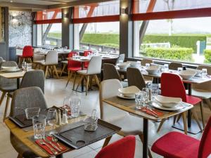 a restaurant with tables and chairs and windows at ibis Saint Rambert d'Albon in Saint-Rambert-dʼAlbon