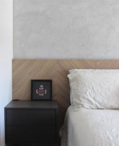 a bed with a nightstand with a clock on it at 1 Dorm - Alto Padrão - 16 Andar - Home Office in Porto Alegre