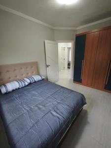 une chambre avec un grand lit avec une couette bleue dans l'établissement Casa de temporada, à Joinville