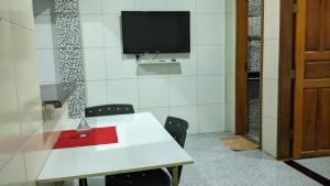 a room with a white table and chairs and a tv at Apartamento aconchegante in Marabá