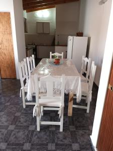 a dining room table with white chairs and a refrigerator at El Coco in Puerto Madryn +9 photos
