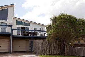 a house with a tree in front of it at Beach holiday in Tomakin