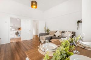 a living room with a couch and a table with wine glasses at Stylish 1BR Flat-Terrace-Free Parking-Rail Station in Croydon
