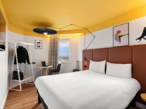 a bedroom with a large bed and a yellow ceiling at ibis Nice Aéroport Promenade des Anglais in Nice