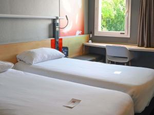 a hotel room with two beds and a window at ibis Saintes in Saintes