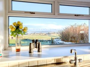 a kitchen window with a sink and a vase of flowers at 3 bed property in Castletown CA416 in Castletown