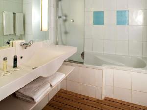 Un baño blanco con bañera y lavabo. en Novotel Lisboa, en Lisboa