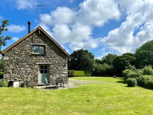 Nevernにある2 bed in Newport Pembrokeshire 78803の野原にテーブルと椅子が置かれた石造りの建物
