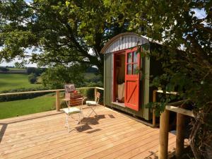 a green cabin with a red door on a deck at 1 Bed in Bickleigh 53296 in Cadeleigh
