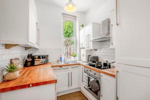 a kitchen with white cabinets and a wooden counter top at Modern 2BR Flat-Terrace-Free Parking-Rail Station in Croydon