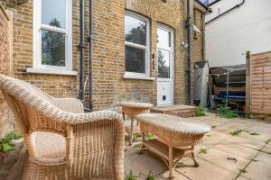 a patio with wicker chairs and a table at Modern 2BR Flat-Terrace-Free Parking-Rail Station in Croydon
