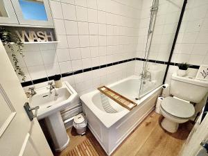 a bathroom with a tub and a toilet and a sink at Modern 2BR Flat-Terrace-Free Parking-Rail Station in Croydon +38 photos
