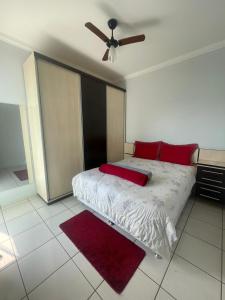 a bedroom with a bed with red pillows and a ceiling fan at Apartamento completo centro in Tangara da Serra