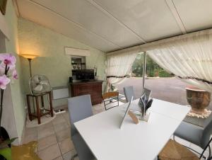 un salon avec une table et des chaises blanches dans l'établissement Chambre d'hôte Petit déjeuner, Sauna et Piscine inclus Jacuzzi en option, à Sarlat-la-Canéda