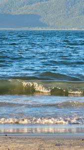 a body of water with a beach and some waves at Lugar Aconchegante 3 in Palhoça