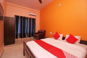 a bedroom with a bed with red pillows and a chair at Hotel O Sunrise in Port Blair +23 photos