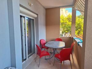 a dining room with red chairs and a table and a window at Apartments by the sea Podgora, Makarska - 2615 in Podgora