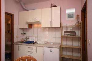 a kitchen with white cabinets and a pink wall at Apartments by the sea Podgora, Makarska - 2615 in Podgora +51 photos