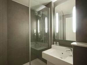 a bathroom with a shower and a sink and a mirror at ibis London Heathrow Airport in Hillingdon +82 photos