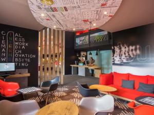 ランスにあるibis Reims Tinqueuxの赤いソファとテーブルと椅子のあるロビー