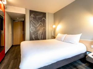 a large white bed in a room with a painting on the wall at Ibis Bourges Centre, Hôtel Restaurant in Bourges