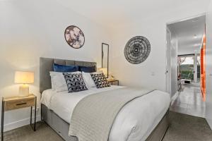 Un dormitorio con una gran cama blanca con almohadas. en Victoria Park Haven w carpark, spa, pool and gym, en Auckland 10 fotos más