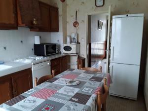 a kitchen with a table and a white refrigerator at Évasion en Berry: Maison proche Voie Verte, Château et Nature - idéal familles et pêcheurs - FR-1-591-55 in Chabenet +3 photos