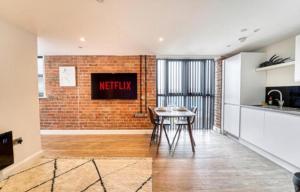 a kitchen with a table and a brick wall at Stay at 52 The Maltings, Burton on Trent - Modern One Bedroom Apartment in Burton upon Trent
