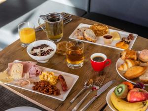 une table en bois avec des assiettes de nourriture et de boissons dans l'établissement ibis Saint-Nazaire - Trignac, à Trignac