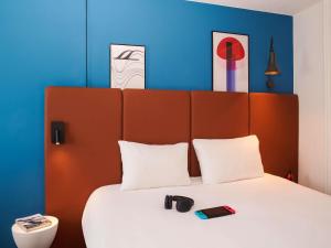 a bedroom with a large bed with two phones on it at ibis Saint-Nazaire - Trignac in Saint-Nazaire