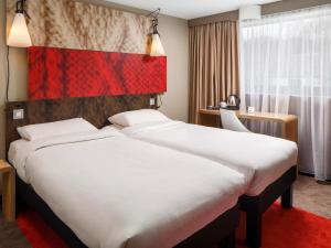 un grand lit blanc dans une chambre d'hôtel dans l'établissement ibis Orleans Centre Gare, à Orléans 53 autres photos