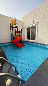 a swimming pool with a red slide next to a building at Liyali Chalet in Taif