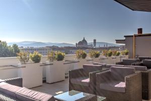 a rooftop patio with chairs and tables and a view at Mh Florence Hotel & Spa in Florence
